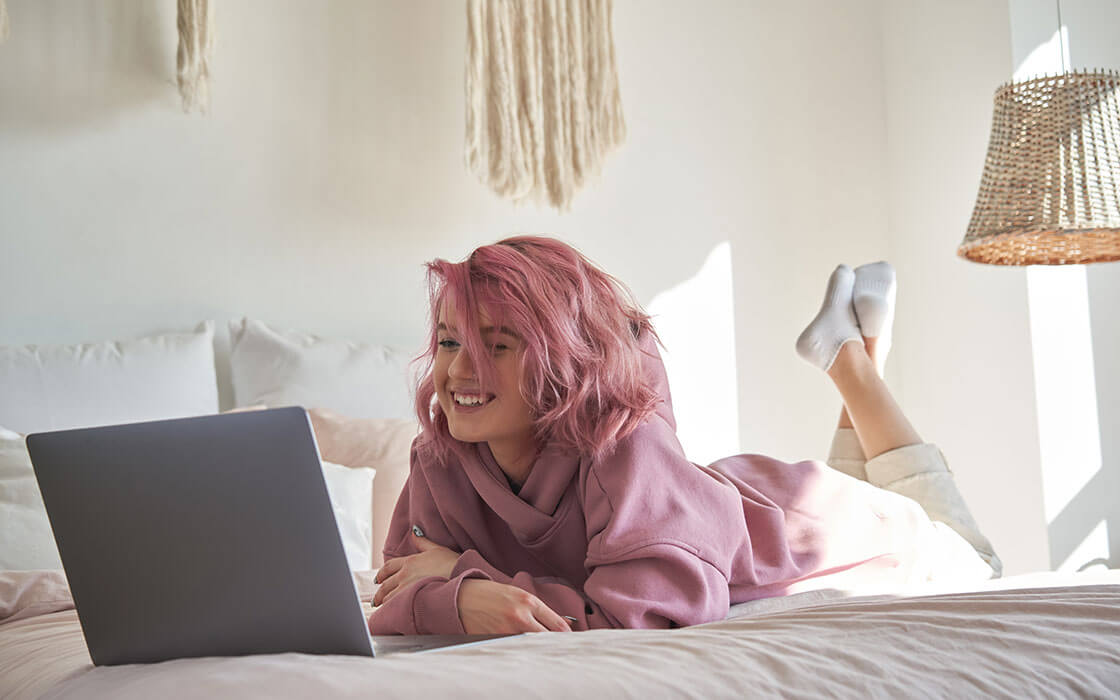 Bewerben mit KI: ein Mädchen liegt mit Laptop entspannt auf dem Bett