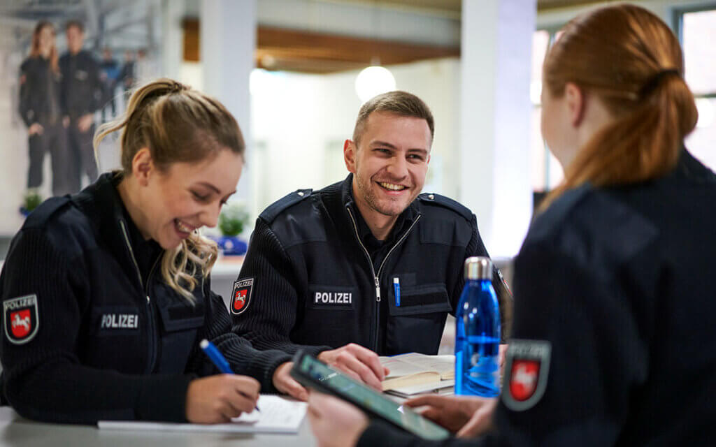 Messe Award auf der Ausbildungsmesse Stuzubi 2025: drei Studierende der Polizeidirektion Hannover sitzen mit Buch und Schreibutensilien an einem Tisch