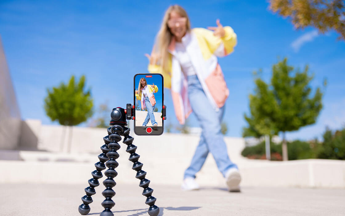 Eine Influencerin läuft über eine asphaltierte Fläche in einem Park und nimmt dabei ein Video auf