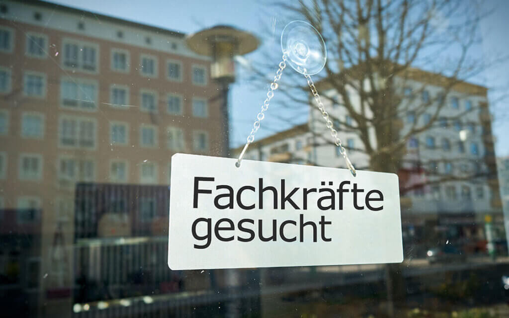 Fachkräftemangel: Risiken und Maßnahmen 1 Fachkräftemangel: Aushang eines Schilds mit der Aufschrift Fachkräfte gesucht am Fenster eines Betriebs in einer Stadt