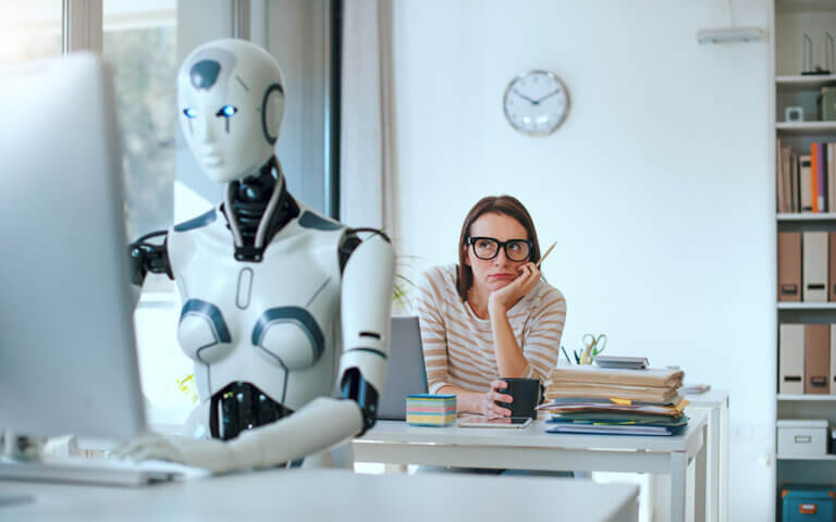 Studien- und Berufswahl in Zeiten von KI, junge Frau sitzt hinter einem humanoiden Roboter im Büro