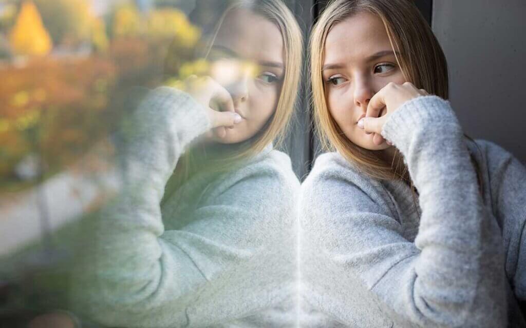 Berufswahl: Welche Jobs sind sicher? Junges Mädchen sitzt nachdenklich am Fenster, spiegelt sich in der Glasscheibe und blickt auf herbstlich bunte Bäume © Adobe Stock